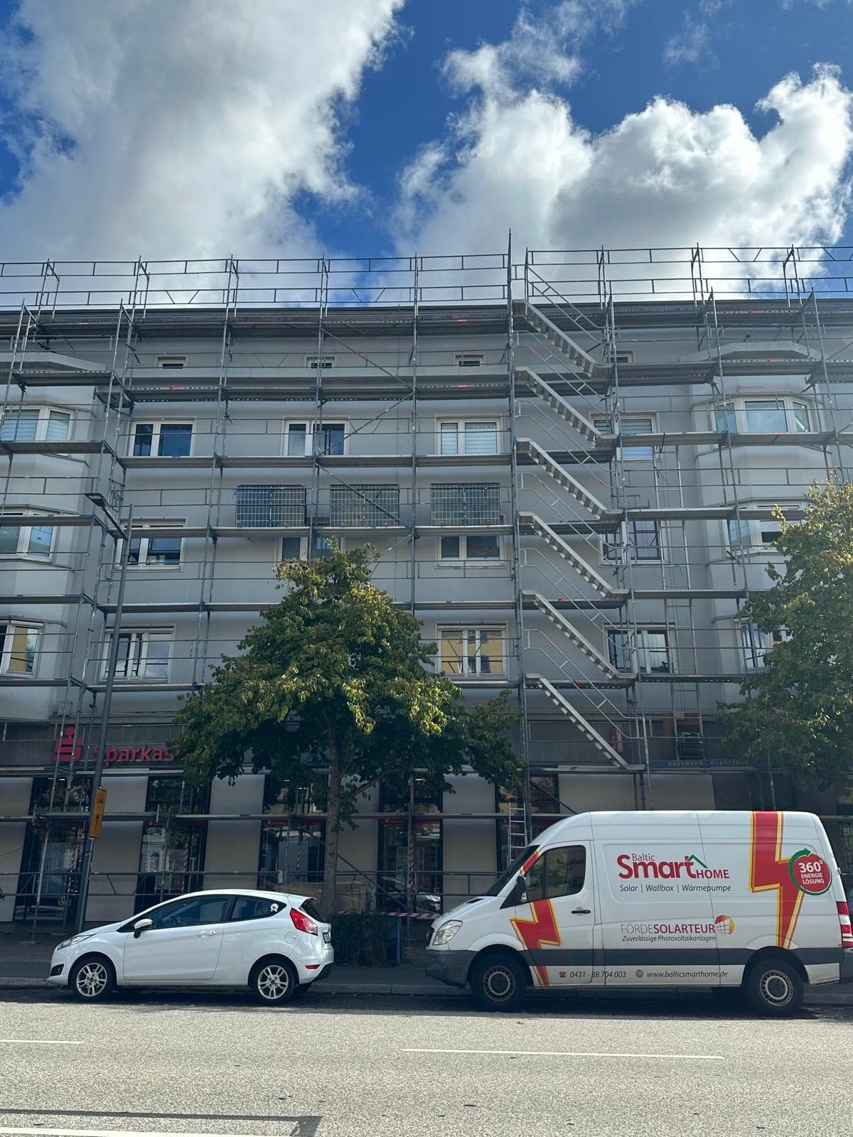 Mehrfamilienhaus mit Gerüst und BSH-Servicefahrzeug während der PV-Installation